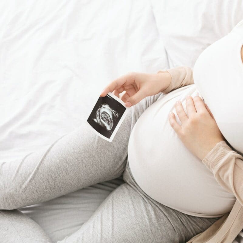 Pregnant woman caressing her belly with sonography